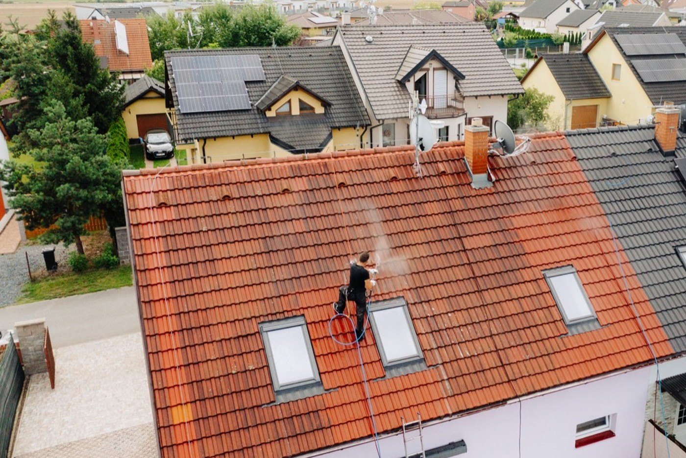 Tlakové čištění taškové střechy z lana, pohled dronem; vpravo sousední střecha s fotovoltaikou